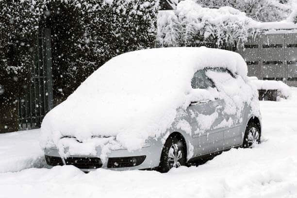 A mid-size car covered in snow.